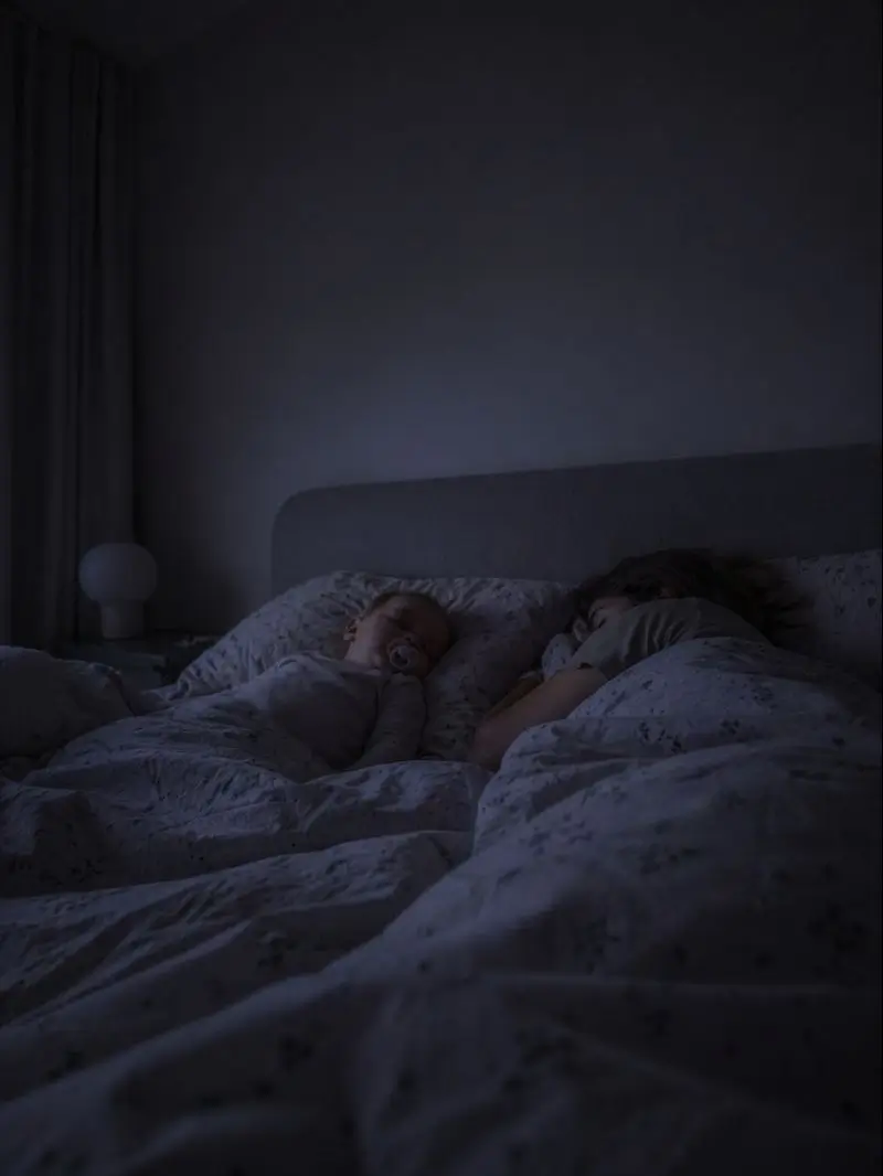 Eltern und Kind schlafen bei gedämpftem Nachtlicht eng beieinander im Bett